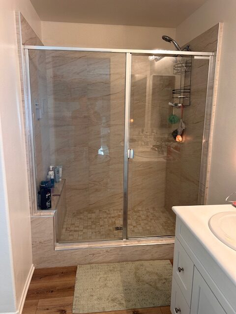 After photo: restored bathroom in Temecula following water damage repairs with glass shower and new tile