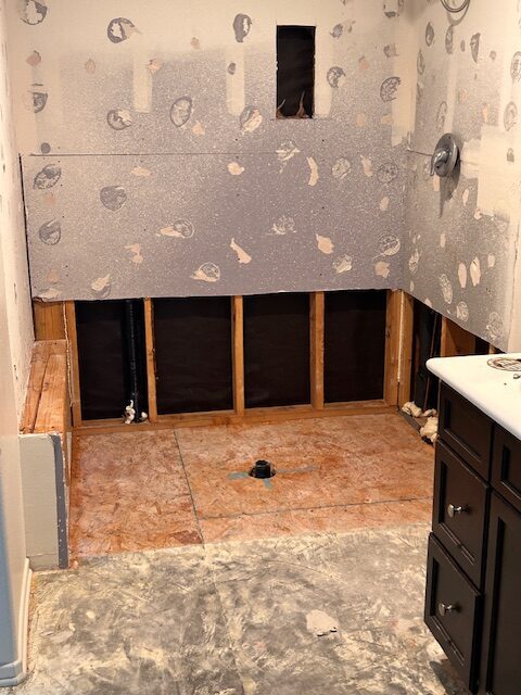 Before photo: bathroom water damage mitigation with lower drywall removed and studs exposed in a Temecula home